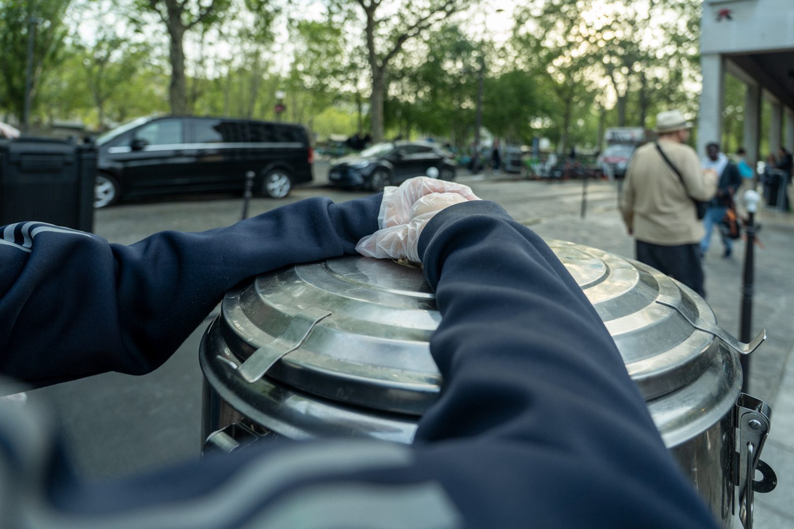 Un bénévole garde la main sur la marmite pendant la maraude, dans la rue